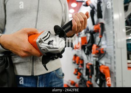 Cloe up of man is looking on new angle grinder at store. Stock Photo