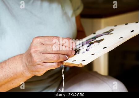 Senior women hands sewing at home, needle work with natural light Stock Photo