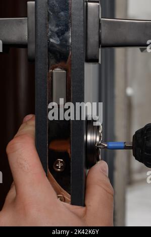 Handyman in uniform changing door lock Stock Photo - Alamy
