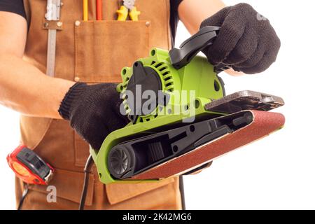 Carpenter in workers apron holding belt electric sander on white background Stock Photo