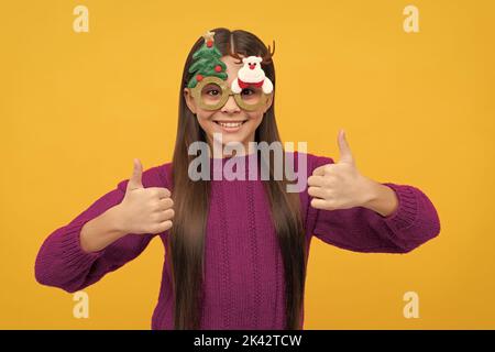 happy child in party glasses showing thumb up on yellow background, christmas Stock Photo