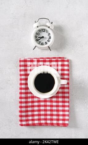 Coffee with alarm clock on light table and red napkin, top view, copy space Stock Photo