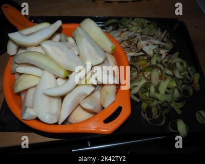pear preservation process. Peels of pear placed on a metal try with an orange bowl full of cleaned and cut up pear fruit. Stock Photo
