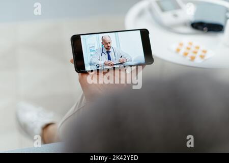 woman using her smartphone to communicate with a home doctor. Stock Photo