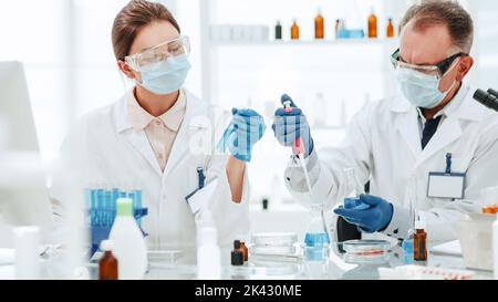 female scientist looks at the liquid in the test tubes . Stock Photo