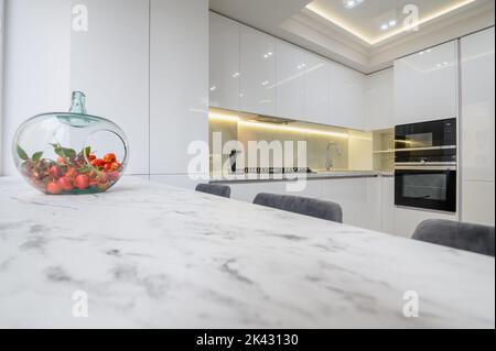 White kitchen interior, a vase with fruits at marble counter top Stock Photo