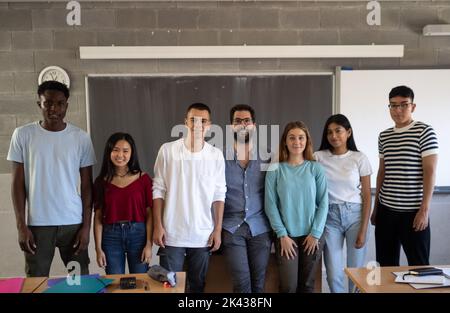 Group of diverse teenage students and a male teacher smiling looking at camera. Stock Photo
