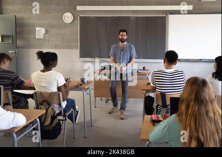 Male teacher explaining the class lesson in a classroom  Stock Photo