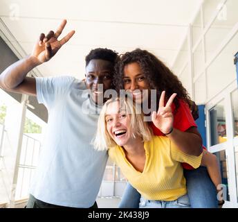Three multi-ethnic young people laughing and having fun on campus Stock Photo