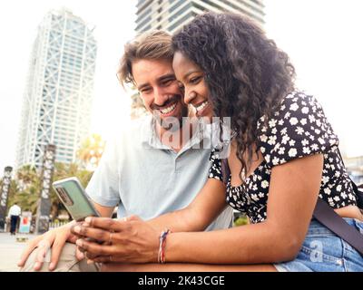 Multi-ethnic heterosexual young couple looking at a mobile phone in the city Stock Photo
