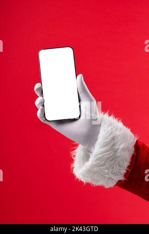 Image of hand of santa claus holding smartphone with blank screen and copy space on red background Stock Photo
