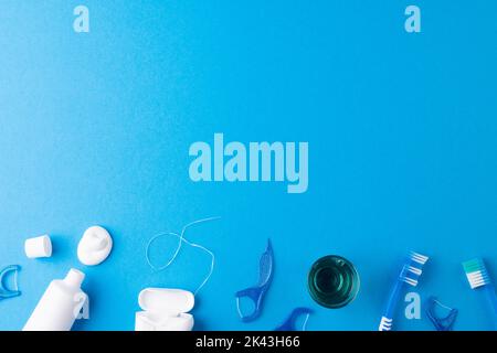 Image of toothbrush, toothpaste, string and liquid on blue surface Stock Photo