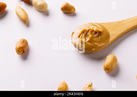 Image of spoon with peanut butter and nuts on white surface Stock Photo