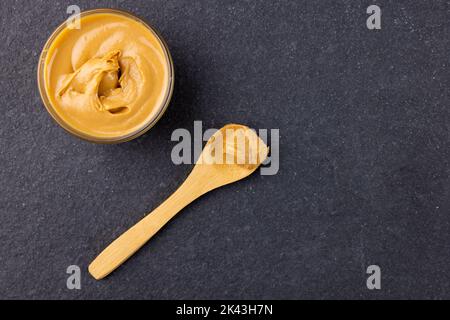 https://l450v.alamy.com/450v/2k43h7n/image-of-spoon-and-bowl-with-peanut-butter-on-dark-grey-surface-2k43h7n.jpg