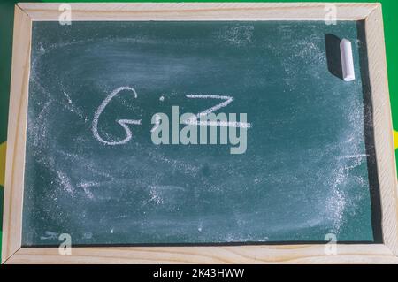 Green chalkboard with the word 'chalk' written in Portuguese with white chalk. Stock Photo