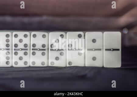 Domino pieces together from number 6 to 0 standing and highlighted, image in long exhibition with hand reflection pleting the pieces. Stock Photo