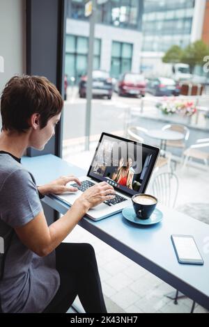 Businesswoman having a cup od coffee while using laptop in office Stock Photo