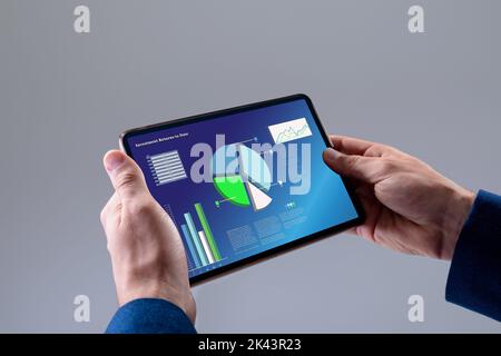 Cropped hands of cuacasian businessman holding digital tablet with infographic data Stock Photo