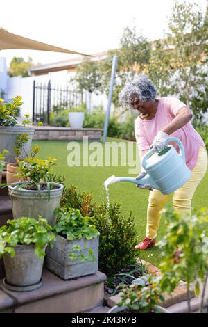 Happy senior african american women watering plants in the garden Stock Photo