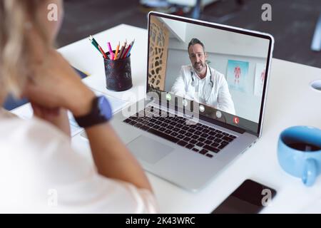 Composition of caucasian male doctor on laptop over caucasian businesswoman in office. Global business and digital interface concept digitally generat Stock Photo