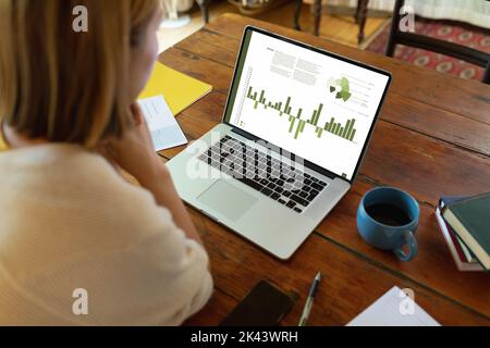 Composition of data processing on laptop over asian businesswoman in office. Global business and digital interface concept digitally generated image. Stock Photo