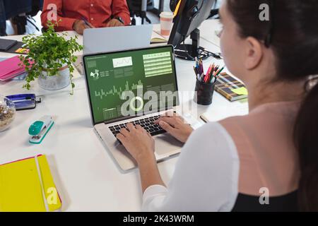 Composition of data processing on laptop over caucasian businesswoman in office. Global business and digital interface concept digitally generated ima Stock Photo