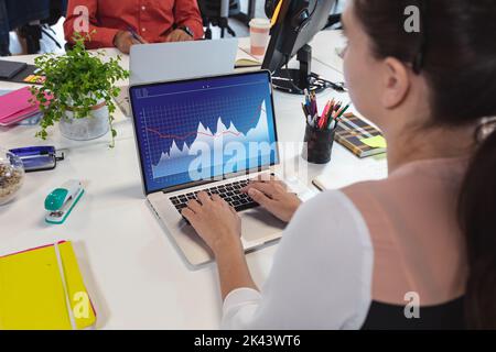 Composition of data processing on laptop over caucasian businesswoman in office. Global business and digital interface concept digitally generated ima Stock Photo