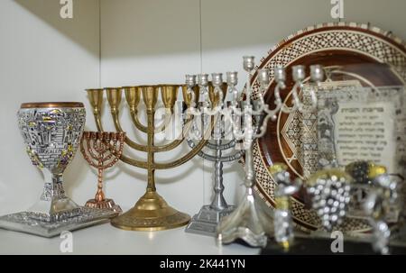 A Kiddush cup with golden hanukkah menorah and Hanukkiah on the shelf. Symbols of Judaism used as tradition for celebrating Jewish festivals. Nobody, Stock Photo