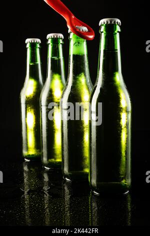 https://l450v.alamy.com/450v/2k442fr/image-of-red-bottle-opener-and-four-green-beer-bottles-with-crown-caps-with-copy-space-on-black-2k442fr.jpg