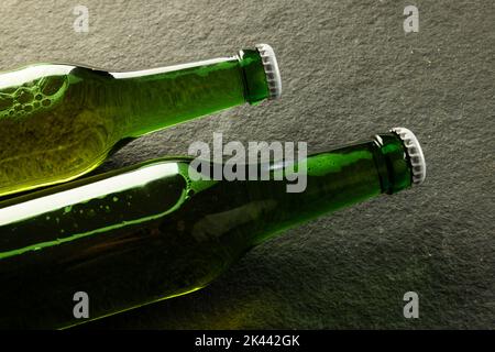 Image of two green glass beer bottles with white crown caps lying on slate, with copy space Stock Photo