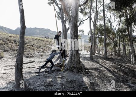 South Africa, Hermanus, Teenage girl (16-17) and brother (8-9) playing on rope swing Stock Photo