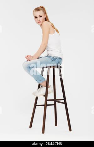 Simplicity is perfection. Portrait of a beautiful young woman on a chair isolated on white. Stock Photo