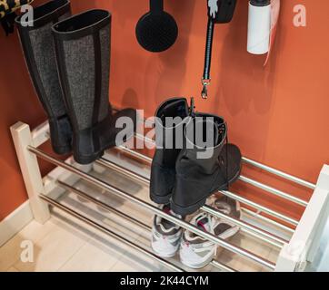 A few pairs of shoes on a shelf in the hallway in the house for the whole family. Shelving rack with stylish shoes Stock Photo