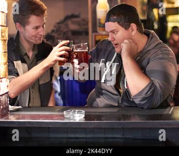 Having a pint with his pal. Two friends drinking at the local bar. Stock Photo