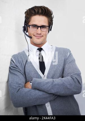 Confident support assistant. A young technical support engineer leaning against a wall. Stock Photo