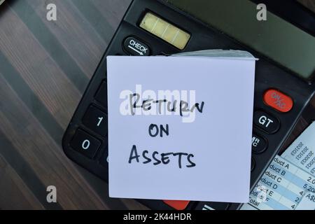 Concept of Return on Assets write on sticky notes with calculator isolated on Wooden Table. Stock Photo