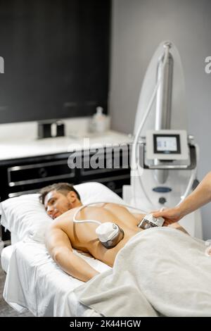Man receiving vacuum roller massage at beauty centre Stock Photo