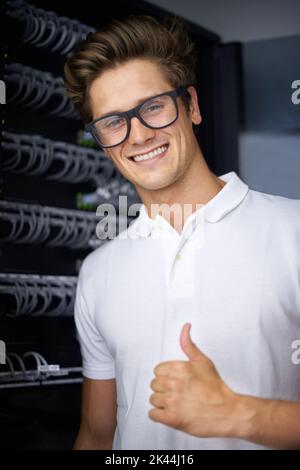 Taking care of your network needs. A happy computer technician in a server room giving you the thumbs up. Stock Photo