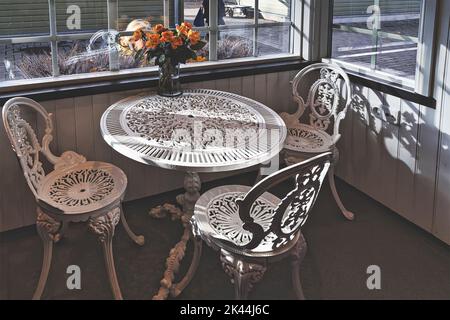 Empty vintage wrought iron garden table and chairs in public cafe inside an autumn day. Stock Photo