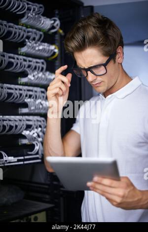 Taking care of your network needs. A confused technician looking at his digital tablet. Stock Photo