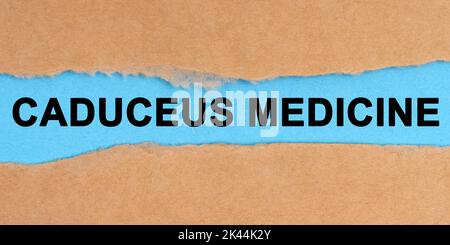 Medicine concept. The paper is ripped in the middle. Inside on a blue background it is written - Caduceus Medicine Stock Photo