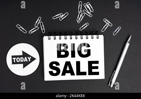 Business concept. On a black background, a round plate - Today and a notebook with the inscription - BIG SALE Stock Photo