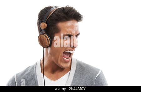 Feeling the groove. A handsome young man enjoying music on his headphones against a white background. Stock Photo