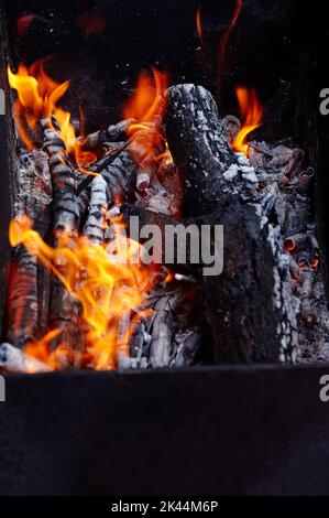 Burning red hot sparks fly from fire. Barbecue gril with glowing and flaming hot charcoal and firewood Stock Photo