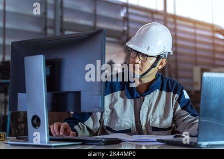 A Male Industrial Engineer Use Technology Works on the Personal Computer. Facility Operator Controls Workshop Production Line. Industry 4.0 Modern Fac Stock Photo