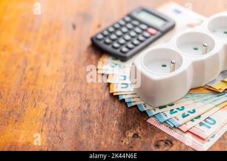 Electric socket and the euro money on the wooden table. Concept of increasing electric prices. Stock Photo