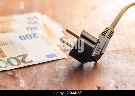 Electric plug and the euro money on wooden table. Concept of increasing electric prices. Stock Photo