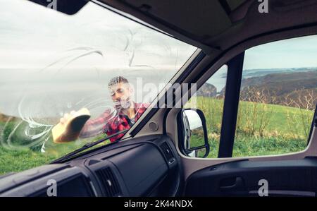 Man cleaning camper van windshield outdoor Stock Photo