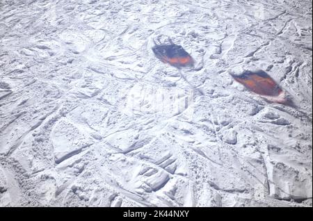 Snow slope with ski tracks. The shadow of ski lifts reflected on the icy ground. Stock Photo