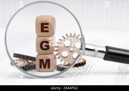 Business concept. There is a magnifying glass on the documents that points to the cubes with the inscription - EGM Stock Photo